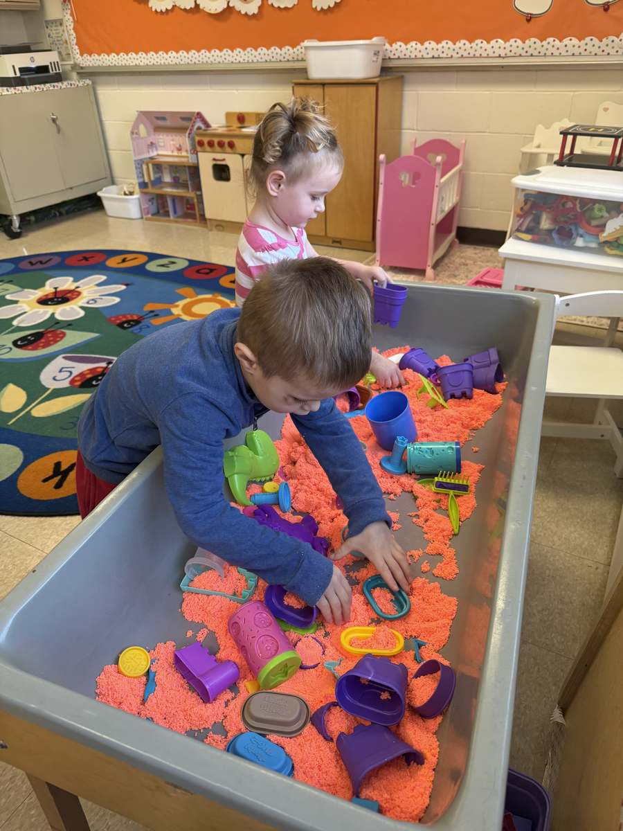 Two children playing together at a sensory table during free play at Humpty Dumpty Nursery School