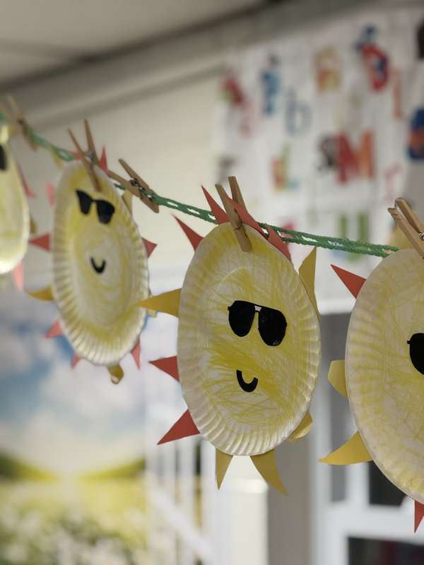 Paper sun cutouts made by children, hanging in the classroom