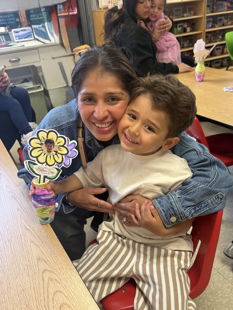 A mother hugging her son at the Humpty Dumpty Mother's Day Breakfast, holding a handmade flower craft